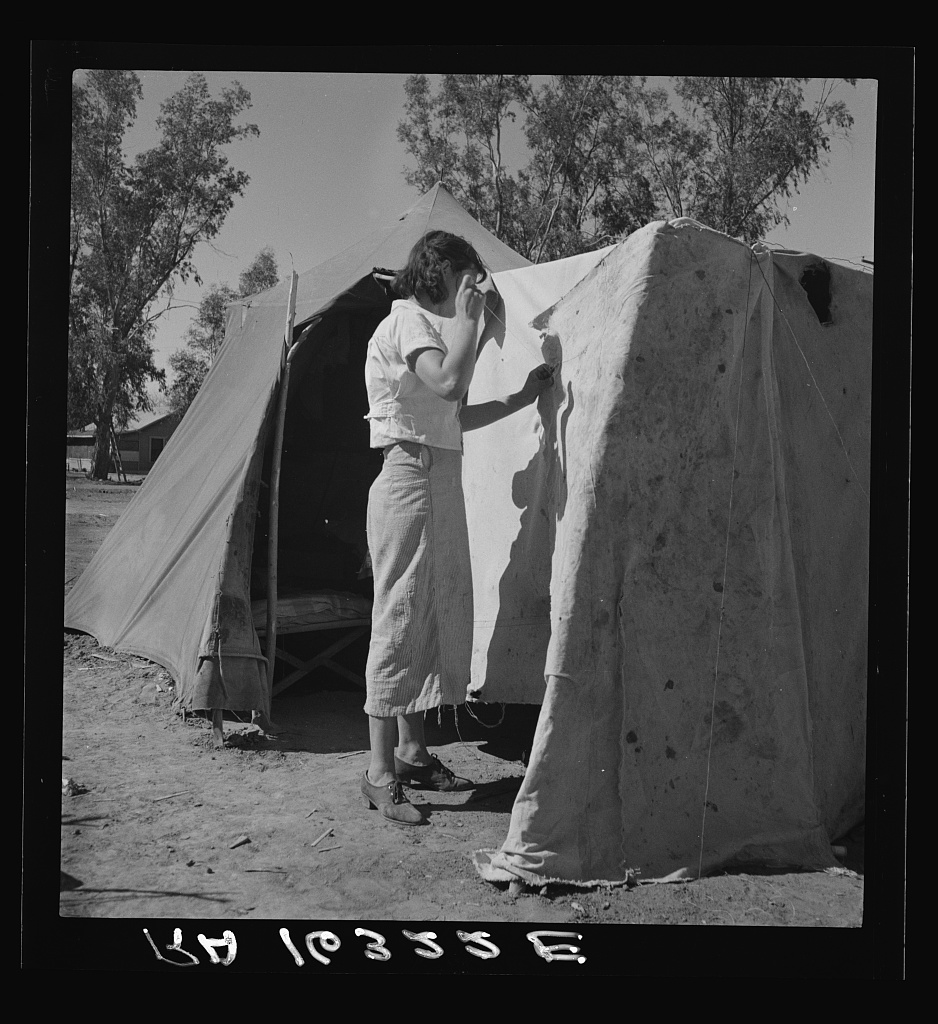Woman in a California pea pickers’ camp, mending the tent